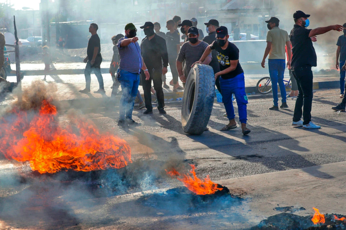 Supporters of hardline Iraqi Shiite factions block streets and burn tires in Basra, Iraq, after the Electoral Commission announced the results of the parliamentary elections on Oct. 17, 2021. (AP Photo/Nabil al-Jurani)