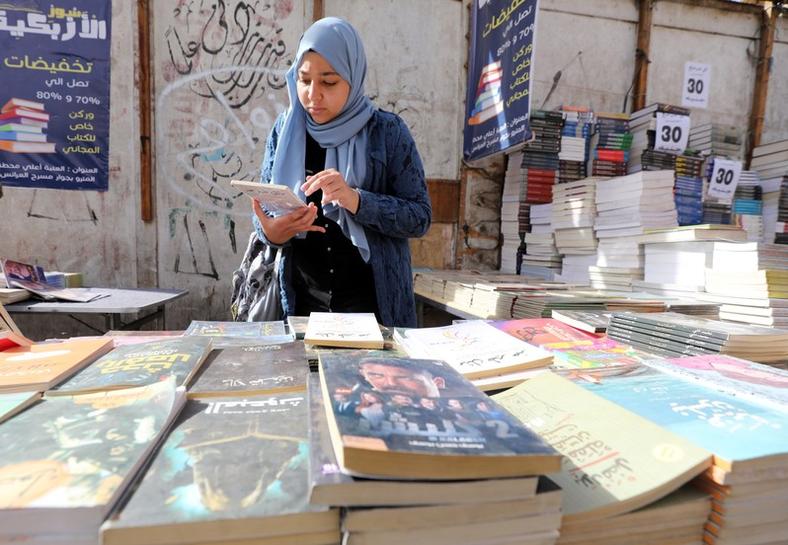 A woman checks a book at the historic Al-Azbakeya book market in Cairo, Egypt, Jan. 15, 2019. (Reuters)