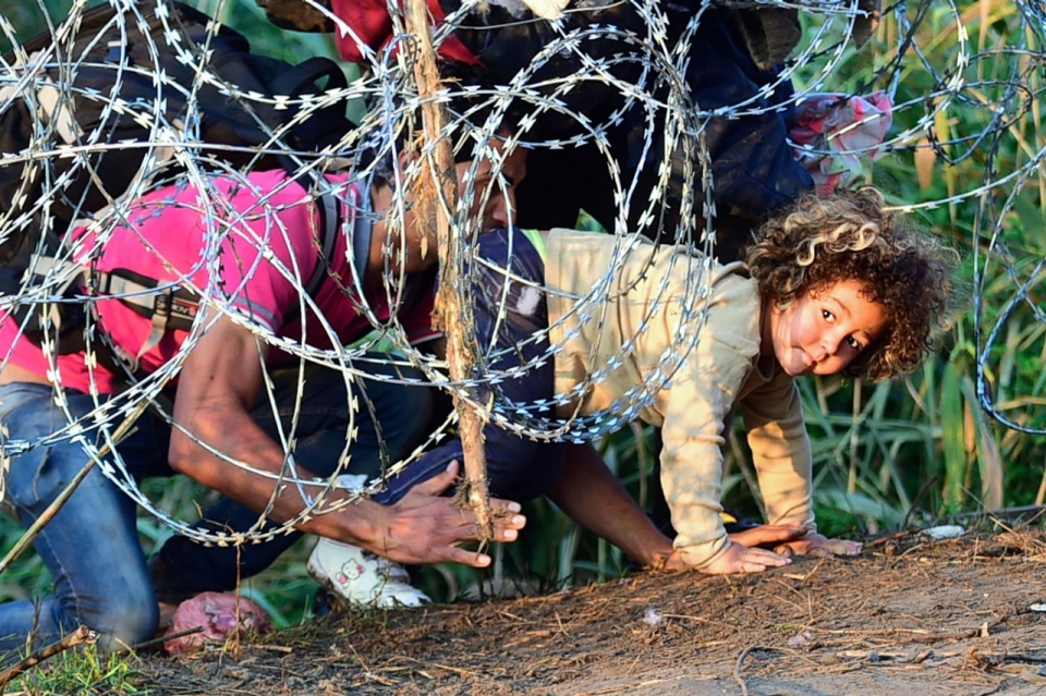 Refugees crawl under barbed wire on the Hungary-Serbia border near Roszke, Hungary, Aug. 27, 2015. (AFP)
