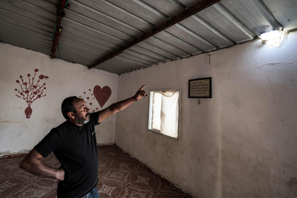 Mohamad Hassouna points to a hole caused by a projectile that injured his daughter Amina in their Negev desert home. (AFP)
