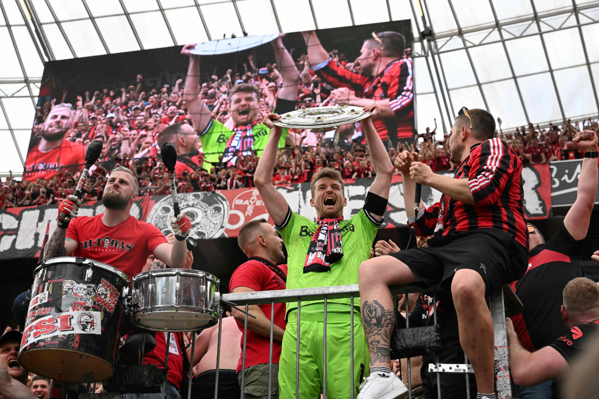 Bayer Leverkusen's Finnish goalkeeper #01 Lukas Hradecky celebrates with the Bundesliga trophy among the fans after the German first division Bundesliga football match between Bayer 04 Leverkusen and FC Augsburg in Leverkusen, Germany on May 18, 2024. (AFP)
