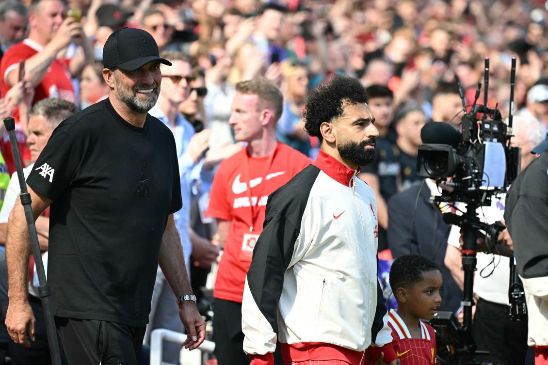Liverpool’s German manager Jurgen Klopp walks out with Egyptian striker Mohamed Salah ahead of kick-off in the English Premier League match against Wolverhampton Wanderers at Anfield in Liverpool on May 19, 2024. (AFP)