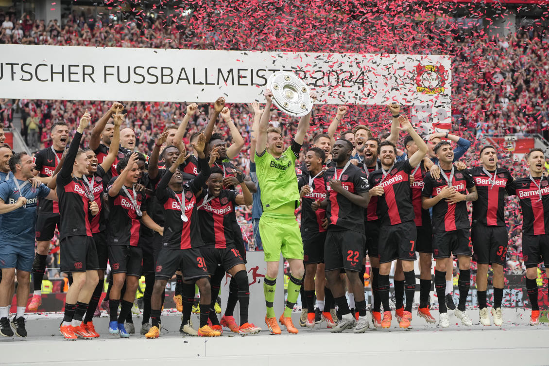 Leverkusen’s players celebrate with the trophy as they won the German Bundesliga match against FC Augsburg at the BayArena in Leverkusen on May 18, 2024. (AP)