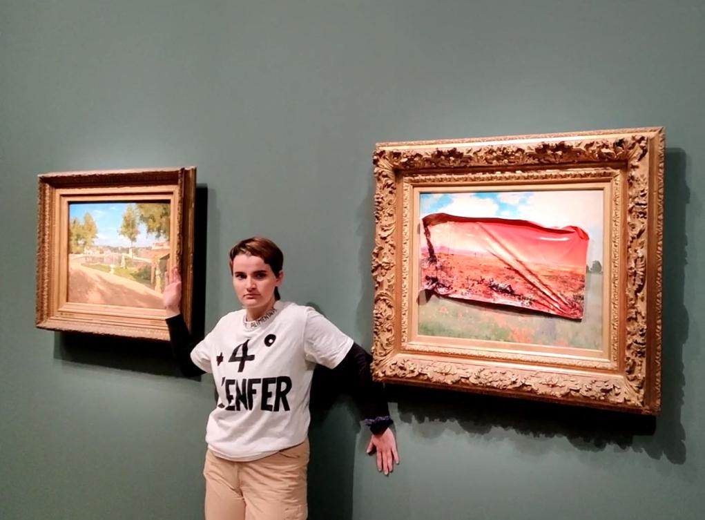 This handout photo taken and released on June 1, 2024, by the Riposte Alimentaire collective shows a member of Riposte Alimentaire wearing a T-shirt reading “+4° the hell” posing after covering Claude Monet’s painting “Les Coquelicots,” with a sticker of the same scene in the year 2100, ravaged by flames and drought, at the Musée d’Orsay (Orsay Museum), in Paris. (AFP/Riposte Alimentaire)