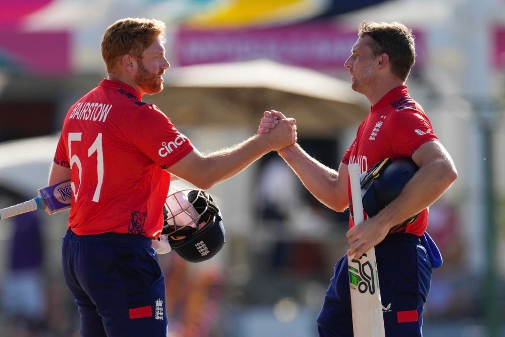 England's captain Jos Buttler, right, and batting partner Jonny Bairstow shake hands at the end of the ICC Men's T20 World Cup cricket match against Oman at Sir Vivian Richards Stadium in North Sound, Antigua and Barbuda on June 13, 2024. (AP)