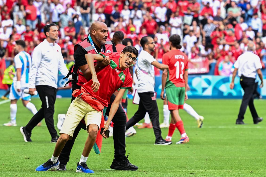 A member of security holds a fan of Morocco after numerous Moroccan fans invaded the pitch at the end of the men’s group B match against Argentina during the Paris 2024 Olympic Games at the Geoffroy-Guichard Stadium in Saint-Etienne on Jul. 24, 2024. (AFP)