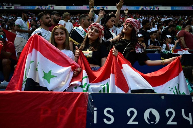 Iraq’s supporters pose for pictures holding flags before the start of the men’s group B football match between Argentina and Iraq during the Paris 2024 Olympic Games at the Lyon Stadium in Lyon on July 27, 2024. (AFP)