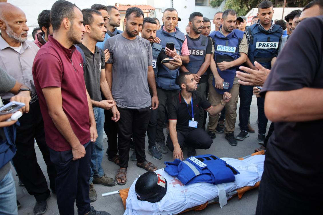 Colleagues of Al-Aqsa TV photojournalist Muhammad Al-Tanani, who was killed during Israeli bombardment in the northern Gaza Strip, stand over his shrouded body at Al-Ahli Arab hospital in Gaza City on Oct. 9, 2024. (AFP)