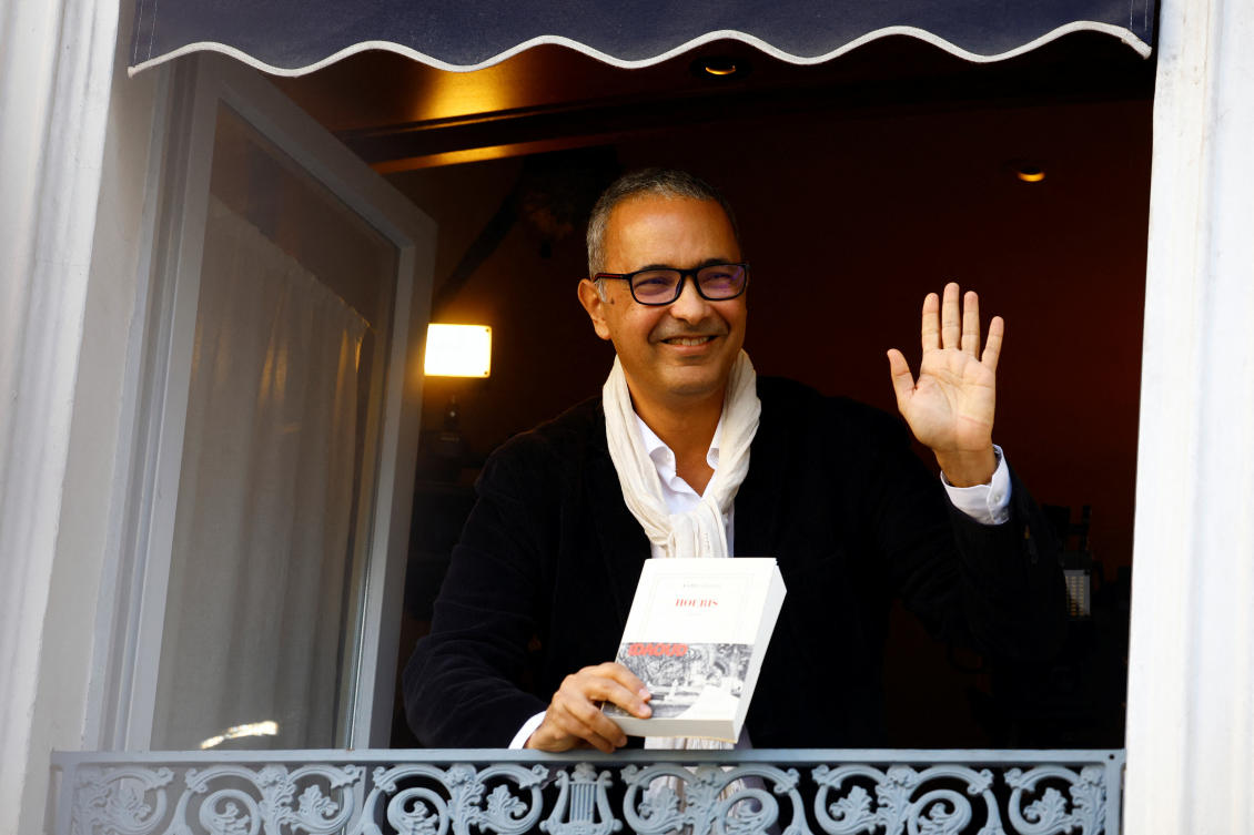 Franco-Algerian writer Kamel Daoud waves from a window of the Drouant restaurant after he received the French literary prize Prix Goncourt for his novel "Houris", in Paris, France, November 4, 2024. (Reuters)