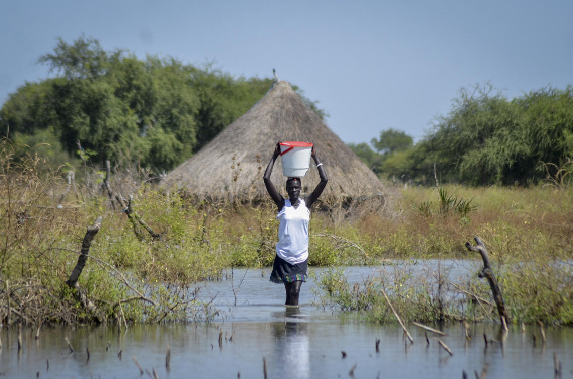 A woman carries a bucket on her head as she wades through floodwaters in the village of Wang Chot, Old Fangak county, Jonglei state, South Sudan, on Nov. 26, 2020. (AP)