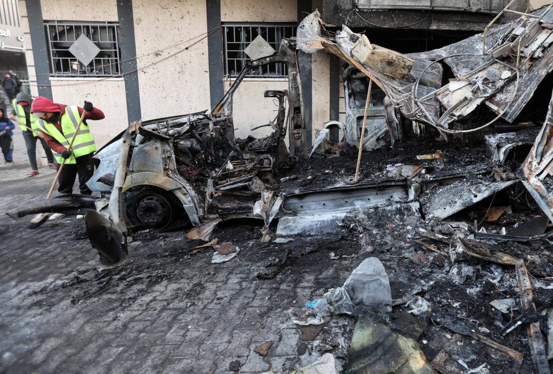 A Palestinian man cleans near the remains of a broadcasting vehicle following an Israeli airstrike that killed five journalists from Al-Quds Al-Youm television channel near Al-Awda Hospital, December 26, 2024. (REUTERS)