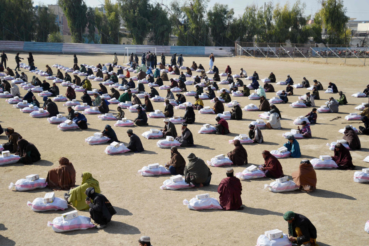 Afghans sit next to winter aid packages distributed by a local charity foundation in Kandahar on Jan. 30, 2025. (AFP)