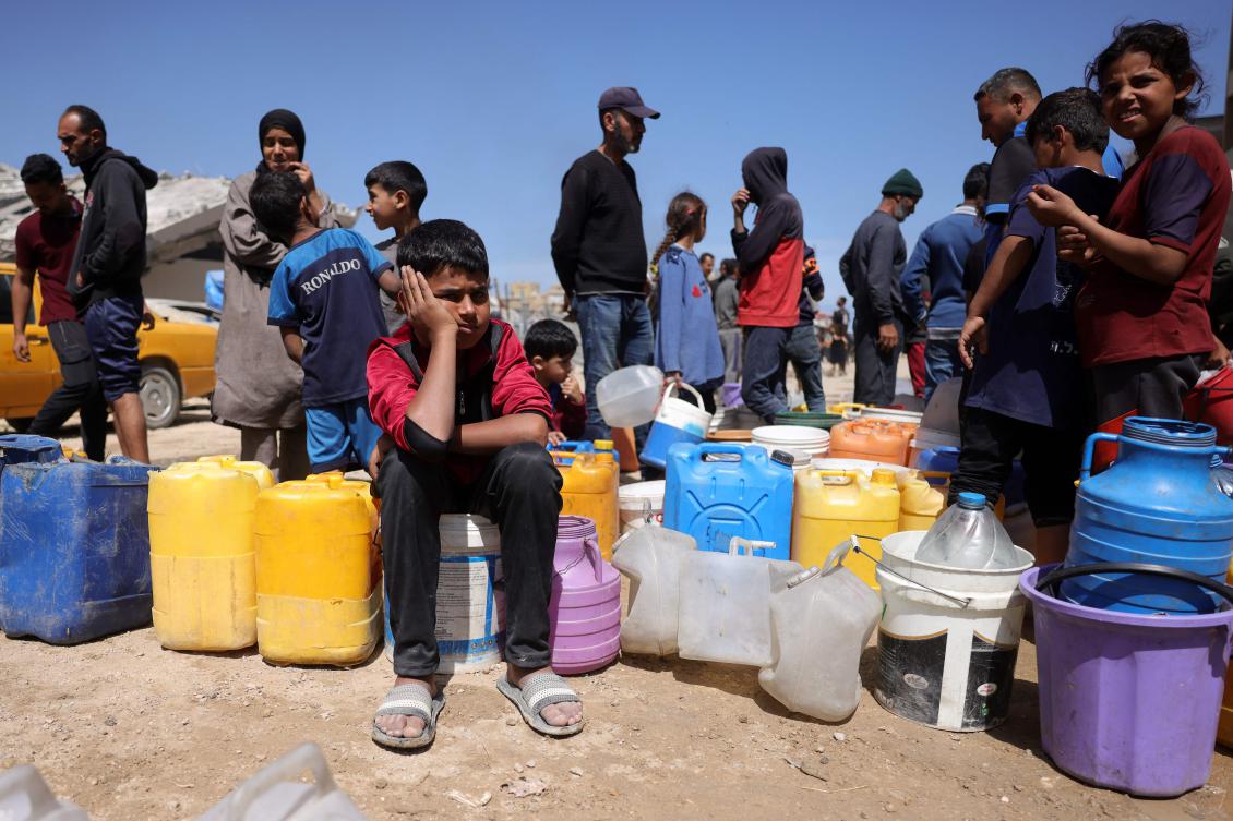Palestinians attempt to collect water at a camp for displaced people in Gaza City, on May 20, 2025. (AFP)