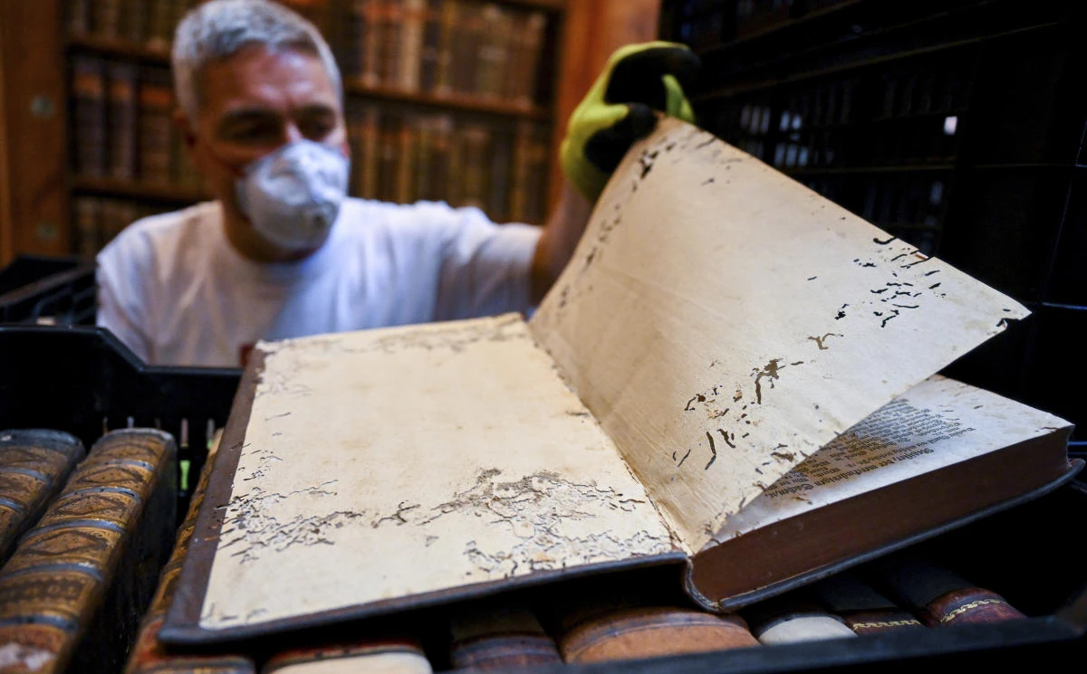 A restorer shows an old book with holes in its pages due to a drugstore beetle infestation at the Pannonhalma Archabbey’s library in Pannonhalma, Hungary on July 3, 2025. (Pannonhalma Archabbey via AP)