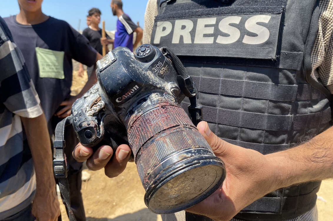 A journalist holds the blood-covered camera belonging to Palestinian photojournalist Mariam Dagga, a journalist who freelanced for AP since the start of the war and who was killed in an Israeli strike on Nasser hospital in Khan Yunis in the southern Gaza Strip, during her funeral on August 25, 2025. (AFP)