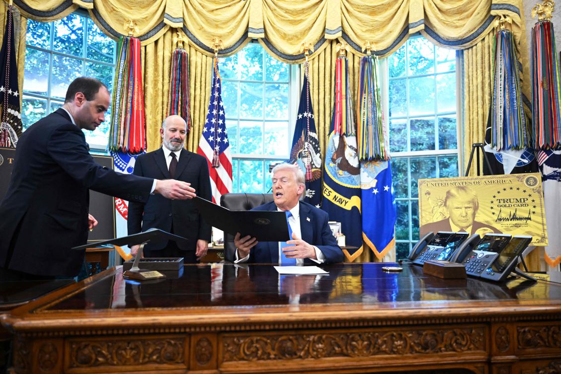 White House Staff Secretary Will Scharf (L) hands an executive order to US President Donald Trump to sign in the Oval Office of the White House in Washington, DC, on September 19, 2025 as Commerce Secretary Howard Lutnick looks on. (AFP)