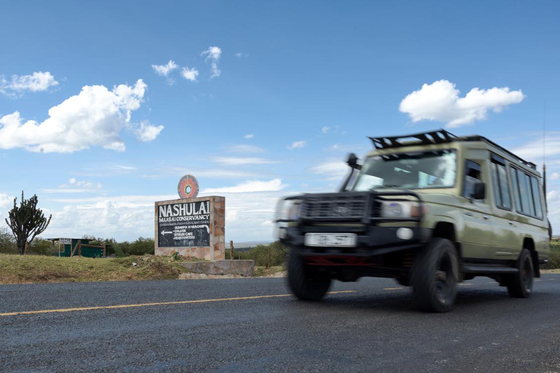 A tourist vehicle drives past a road sign advertising the Nashulai Maasai Conservancy. (AFP)