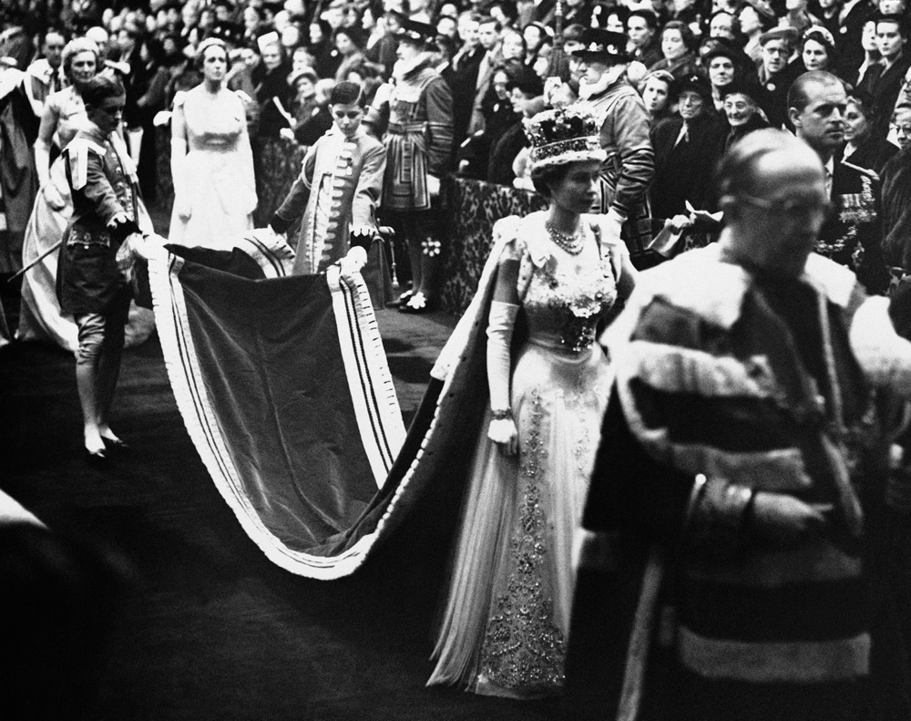 Queen Elizabeth II, wearing the imperial crown, walks through Royal gallery to the House of Lords chamber to officiate the opening of a new session of British Parliament in London, Nov. 30, 1954. (AP/File)