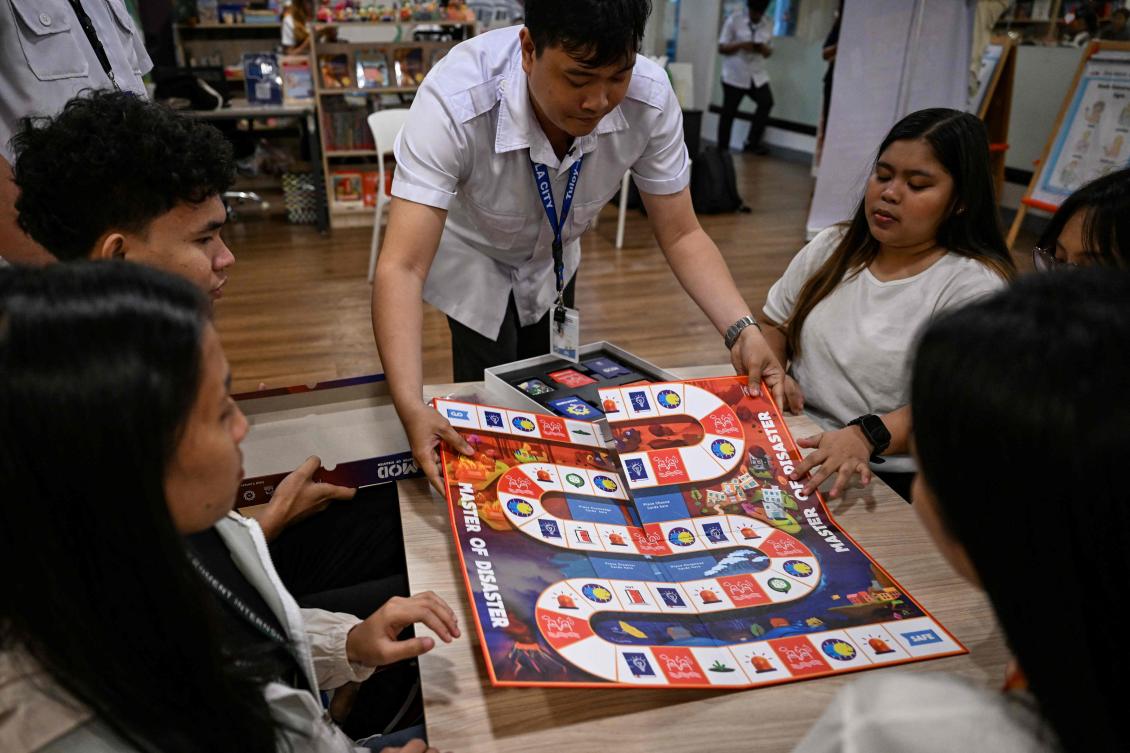 In a library in the Philippines, a dice rattles on the surface of a board before coming to a stop, putting one of its players straight into the path of a powerful typhoon. (AFP)