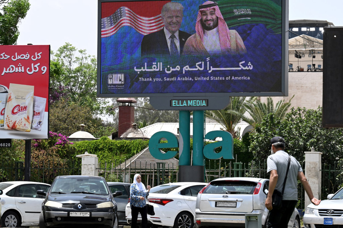 People walk past a billboard thanking Saudi Arabia and the United States, in Damascus on May 14, 2025. (AFP/File)