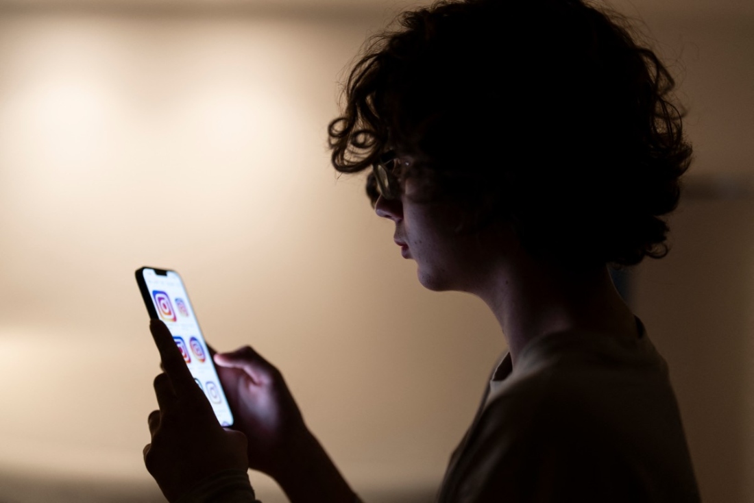 A teenager scrolling through social media apps on his phone. (AFP)