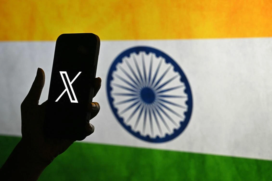 (FILES) This photo illustration shows a person holding a smartphone bearing the logo of X, formerly known as Twitter, in front of the Indian national flag in Bengaluru on January 15, 2026.(AFP)