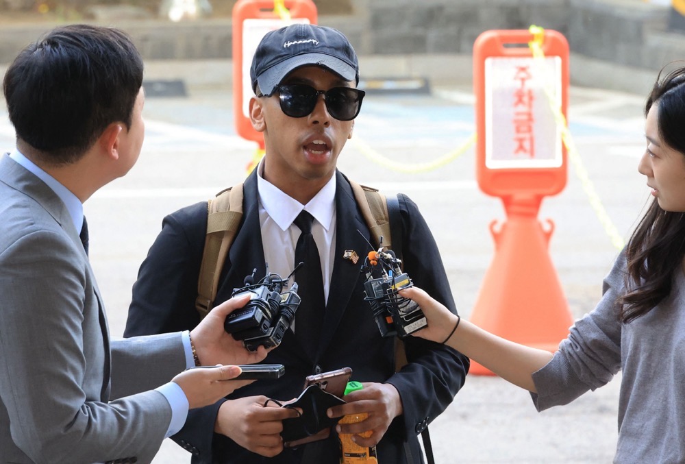 US YouTuber Johnny Somali speaks to reporters as he arrives at a court to attend his trial over charges including obstruction of business and violations of minor public order laws, at the Seoul Western District Court in Seoul on April 15, 2026. (YONHAP/AFP)