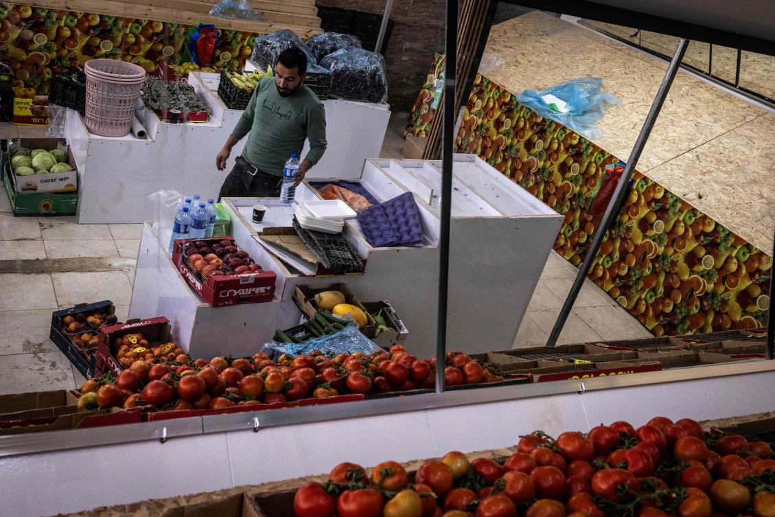 A Palestinian worker clears out fruit and vegetable stalls at his shop ahead of the arrival of an Israeli army demolition team, in the Israeli-occupied West Bank town of al-Eizariya, bordering east Jerusalem, on May 11, 2026. (AFP)