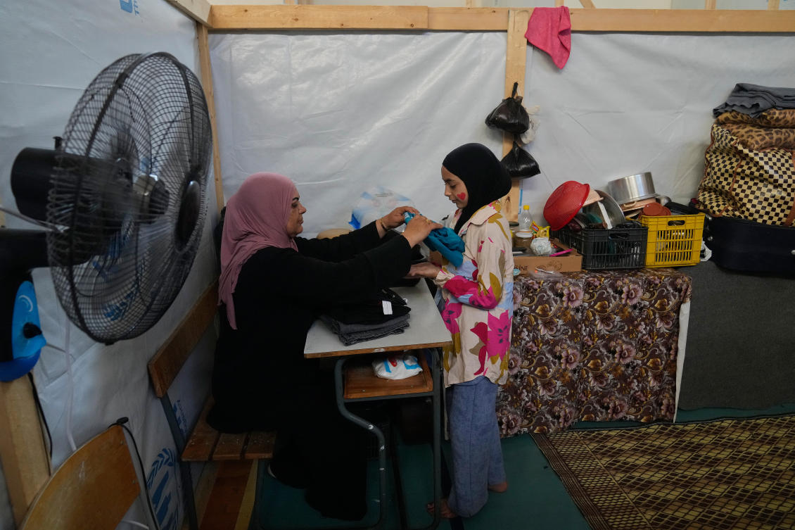 Displaced Randa al-Taki, 51, and her daughter Fatima Khashab, 11, arrange their clothes inside a makeshift room that was set on a basketball court inside a public school turned into a shelter for people whose villages in southern Lebanon were destroyed or occupied by Israeli forces, in Tyre, southern Lebanon, Thursday, Aug. 27, 2026. (AP)