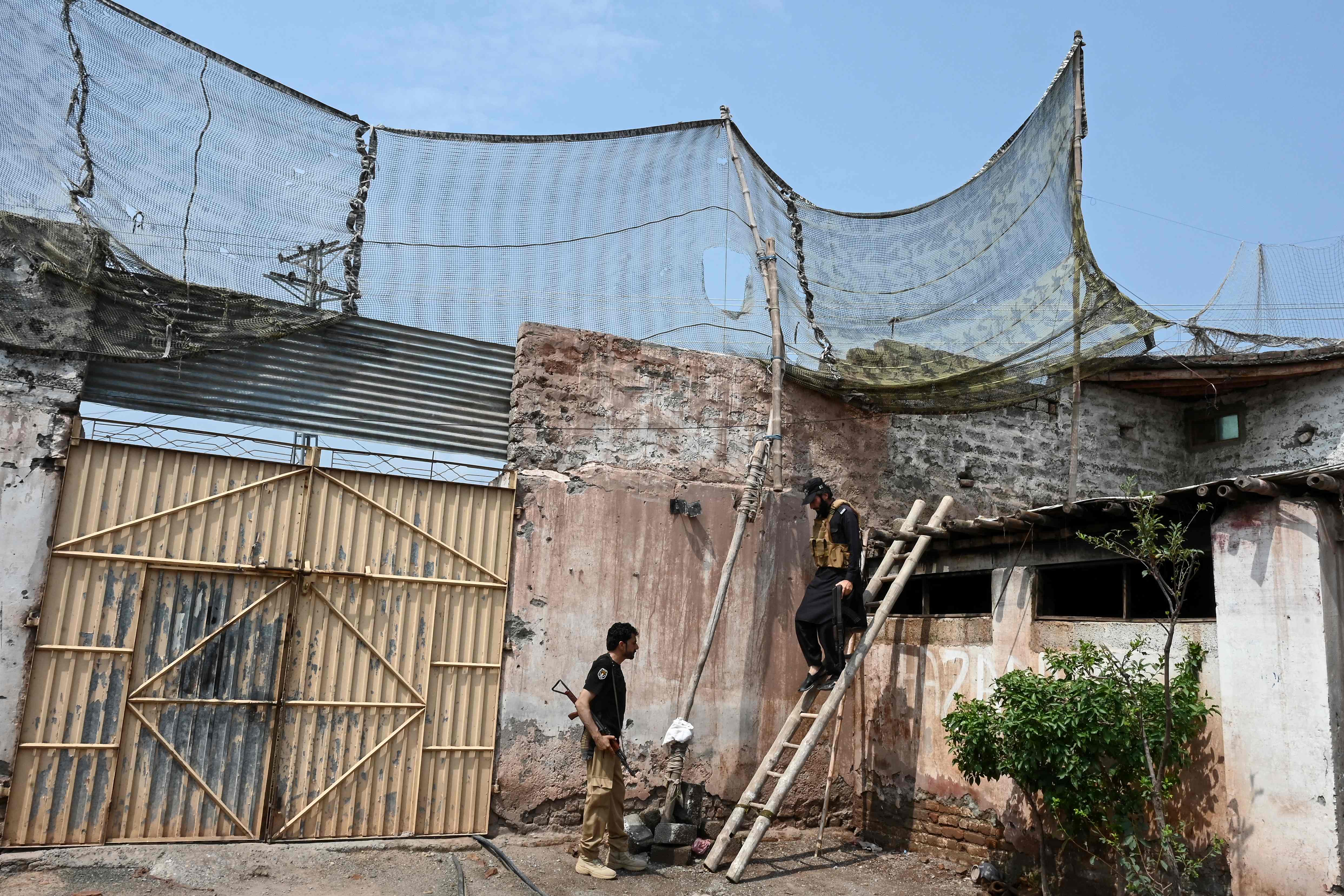This photograph, taken on August 4, 2026, shows a security personnel climbing down a ladder after fortifying a police post with Ukraine-style mesh barriers, forming a new line of defense against militant drone and aerial attacks in Bara, Khyber Pakhtunkhwa province, Pakistan. (AFP)