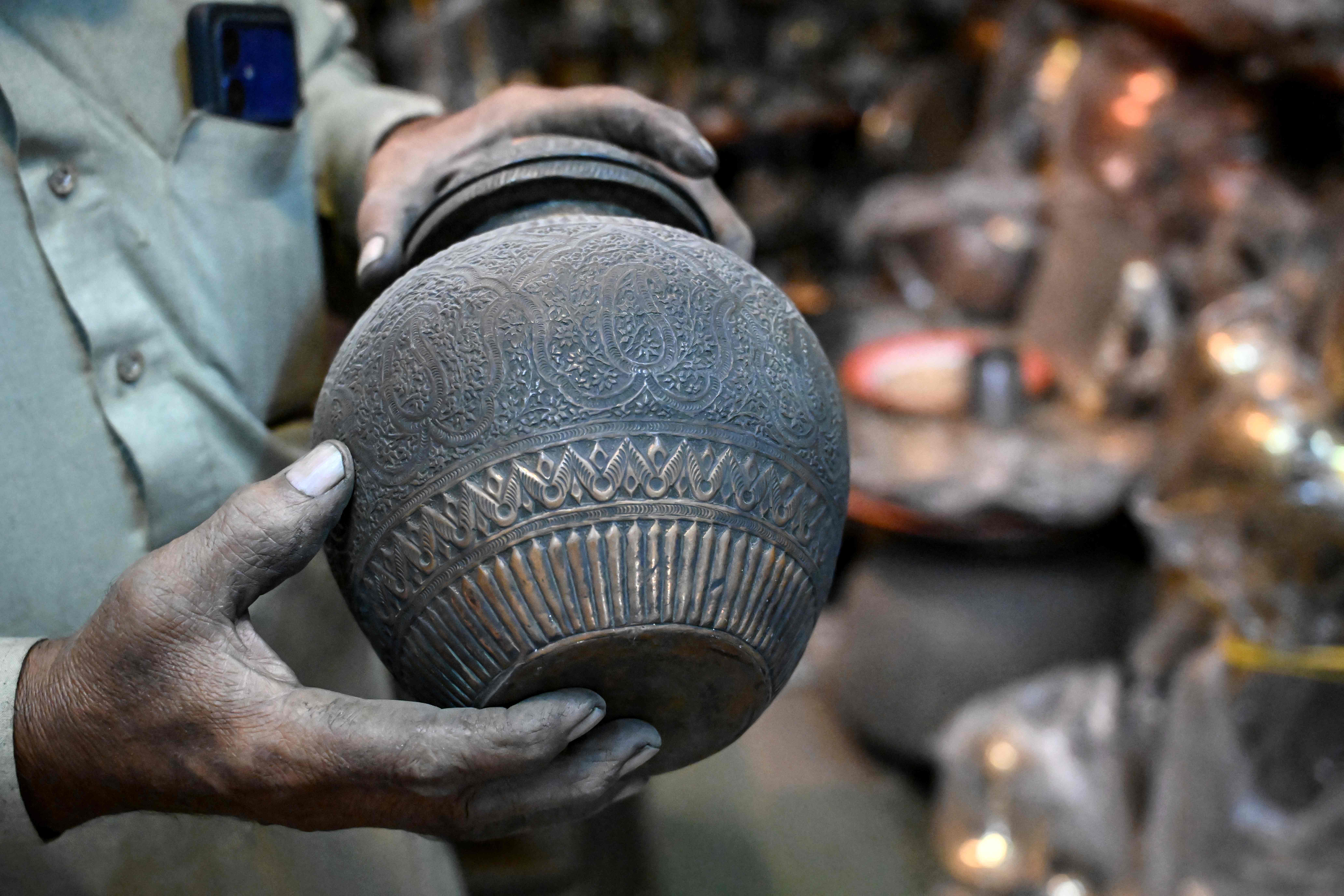 Antique dealer Ahsan Shakeel shows an artefact at his shop selling vintage items in Rawalpindi on October 20, 2026. (AFP)