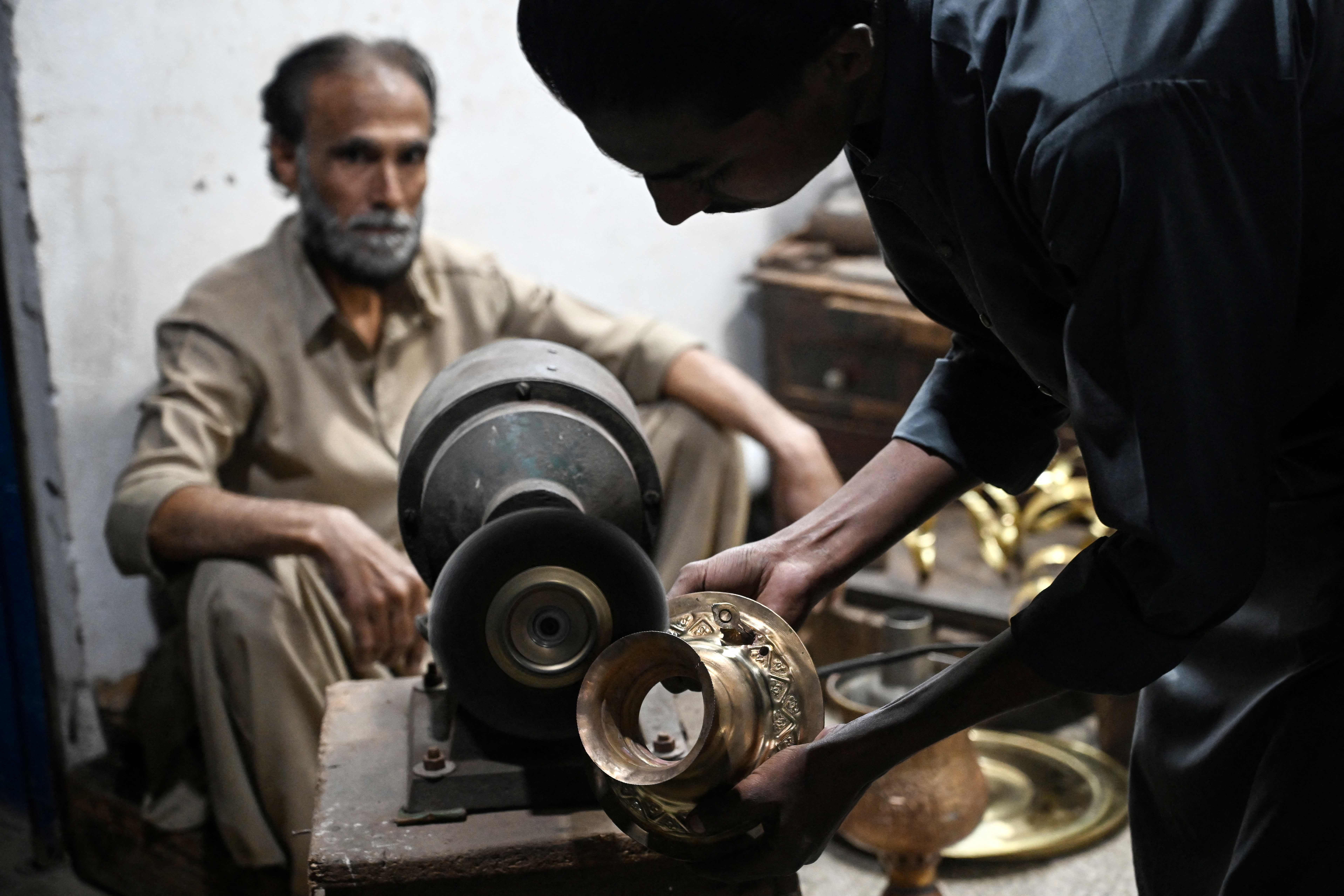 Antique dealer Shakeel Ahmed watches as his son polishes an artefact at their restoration workshop in Rawalpindi on October 20, 2026. (AFP)
