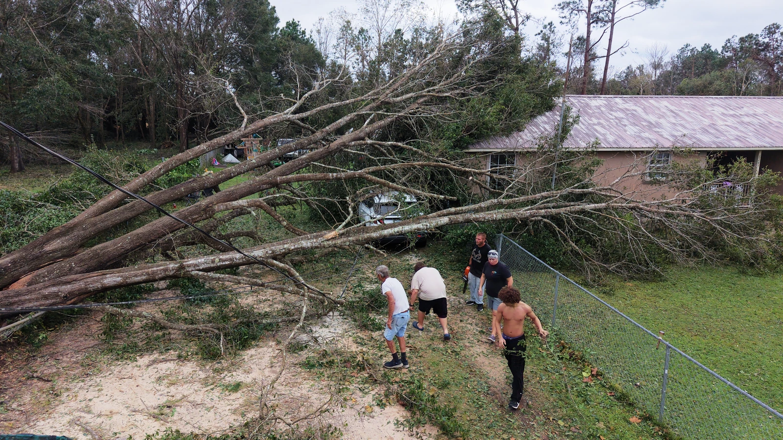 Johnny Ray Wood, and his son Johnny Ray Wood II cut downed trees with other helpers in front of their home in the aftermath of Hurricane Isaias in Milton, Oct. 10, 2026. (AP)